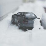 Czarny model samochodu częściowo zasypany śniegiem zimą