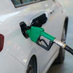 Tankowanie białego auta zieloną dyszą na stacji benzynowej