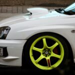 Białe auto z neonowożółtymi felgami na miejskiej ulicy