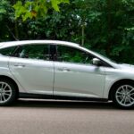 Biały hatchback na ulicy w słońcu, podkreślone lekkie felgi auta