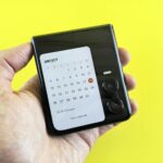 Dłoń trzymająca składany smartfon z kalendarzem na żółtym tle
