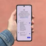 Dłoń trzymająca smartfon z ekranem ustawień Google na jednolitym tle