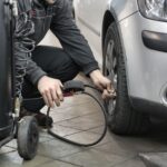 Mechanik w warsztacie sprawdza i ustawia ciśnienie w oponie auta