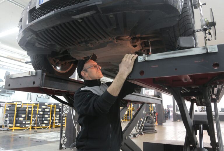 Mechanik sprawdza zawieszenie samochodu na podnośniku warsztatowym